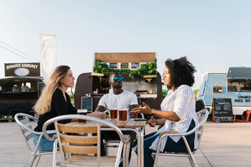 Diverse friends resting near food trucks