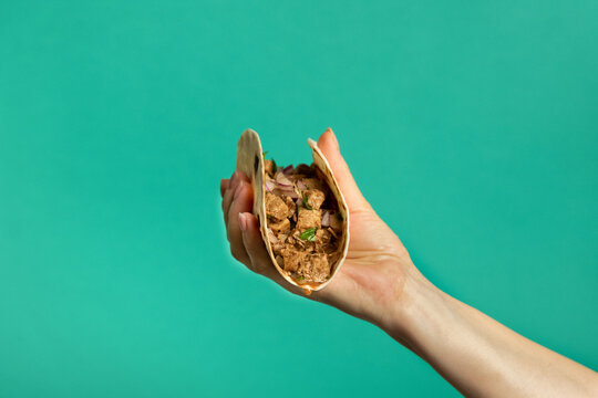 Hand holding Mexican pork tacos carnitas