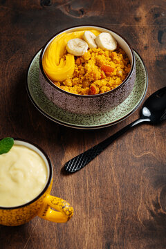 Cup of mango lassi and upma with mango on a table