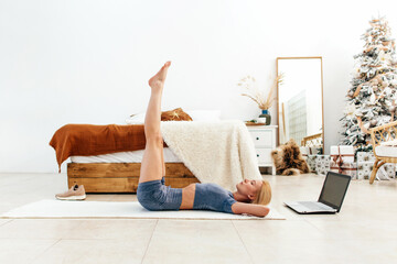 Woman training abdominal muscles by lifting legs up lying on back on floor