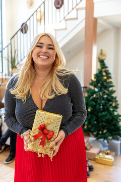 Woman Smiles Holding Holiday Present at Home
