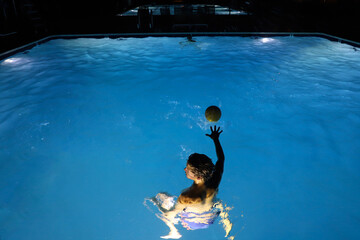 Young man playing water polo at night