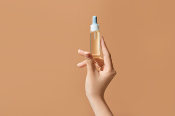 Transparent dropper bottle with serum lotion in female hand