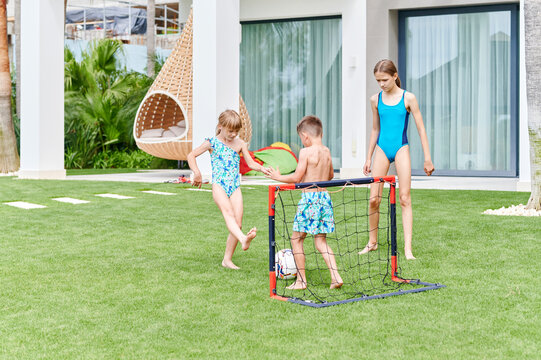 Young children playing soccer on their lawn