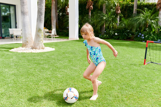 Little girl playing soccer in her backyard