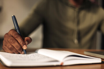 close-up of a hand writes in a notebook with a notepad at the table. a man writes with a pen in a notebook