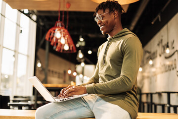 African man with laptop sitting at desk, with laptop on his lap. distance communication, training. online communication