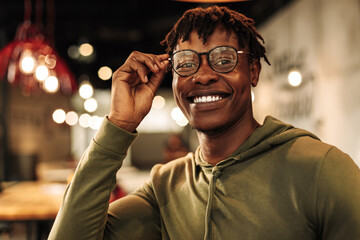 close-up portrait of handsome African American man wearing glasses, smiling and looking at camera.