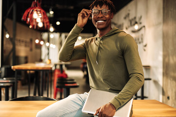 portrait of an American African man with a laptop in his hands, sitting at the desk in the office, in the classroom