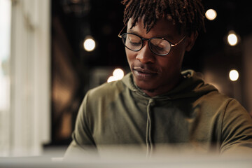 close-up african man in glasses with laptop at the table. distance learning. office worker with laptop. online call.