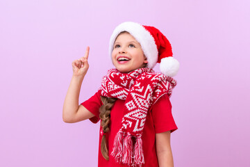 A little girl in a red New Year's scarf and a festive hat points her finger up at the advertisement.