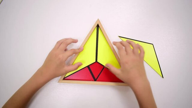Video Top view of girls hand is playing and sorting a puzzle of colored wooden geometric shapes in montessori school. Concept of using a mathematical geometry learning resources for children education