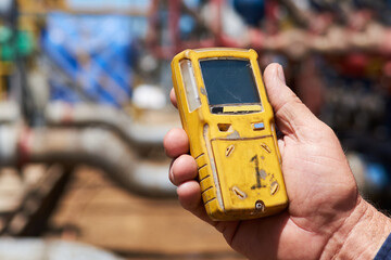 Worker at gas drilling site hoarding gas detection monitor