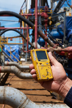 Worker at gas drilling site hoarding gas detection monitor