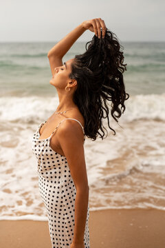 Woman standing on the shore and pulling her hair 