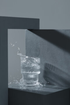 A splash of a water in a transparent glass on black podium