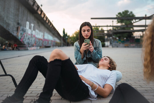 Guy relaxing near girlfriends with smartphone