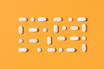 A lot of neatly ordered pills on a bright yellow background