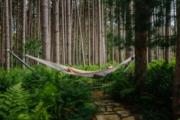 Female relaxing on a hammock by a forest