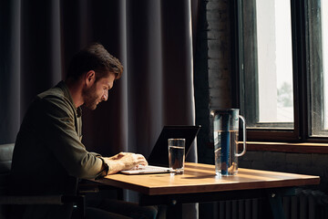 Young bearded guy working at a laptop in a loft