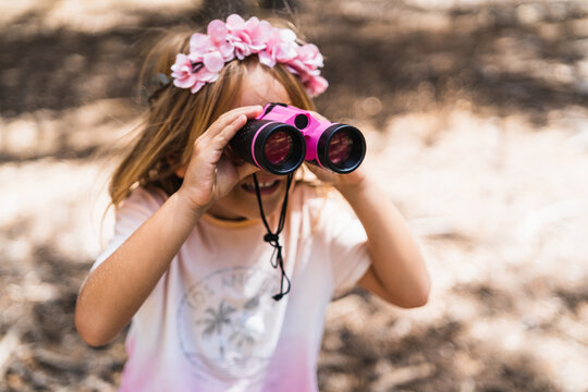 Cheerful girl using binoculars in nature