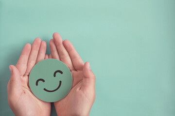 Hands holding green happy smile face paper cut, good feedback rating,positive think, customer review, satisfaction survey ,assessment, child wellness,world mental health day, Compliment Day concept - 463723533