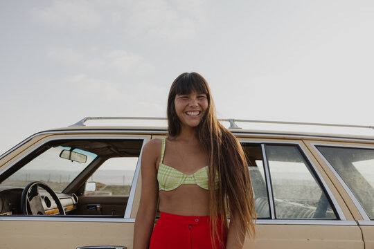 woman smiling in front of vintage car