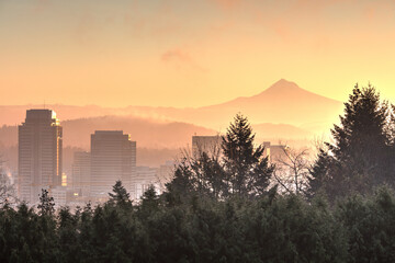 Fogyy golden sunrise over Portland, Oregon skyline with Washington Park in foreground and Mt. Hood...