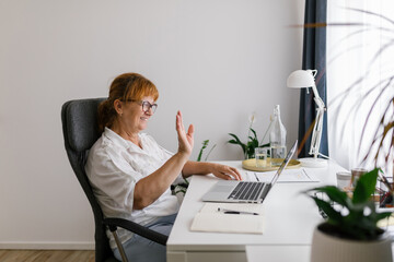 Happy senior woman using laptop at home 