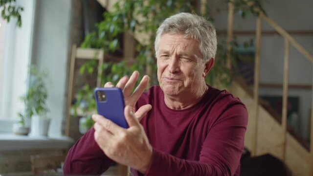 Old man ends a phone call and waves his hand