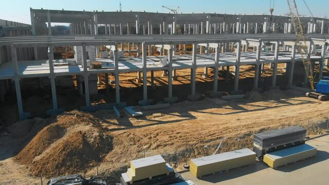 Construction site development. Aerial drone shot of large metallic and marble cement building of new factory or warehouse.
