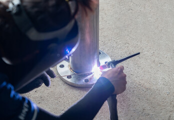 Welder welding stainless steel pipe at industry.