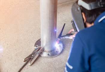 Worker welding of stainless steel pipe by electric arc welding.