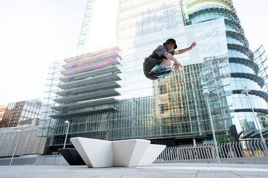 Young man with roller skates jumping in the city