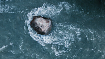 large stone rock in the middle of a river flow