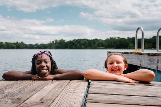 Smiling black and Caucasian girls by a lake pontoon