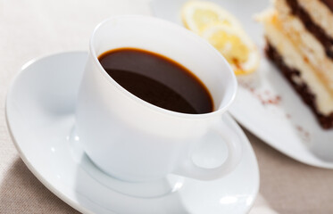 Cup of coffee served with slice of delicious chocolate lemon cake