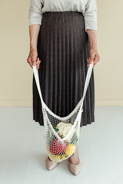 Crop senior woman with groceries in mesh bag