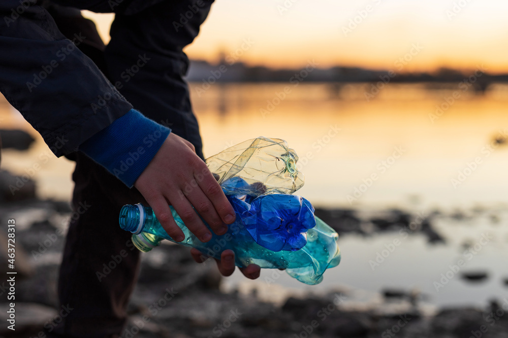 Wall mural a volunteer collecting plastic on the shore. sustainable development concept