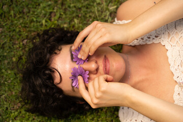 Portrait of cute  woman laying on grass with flowers