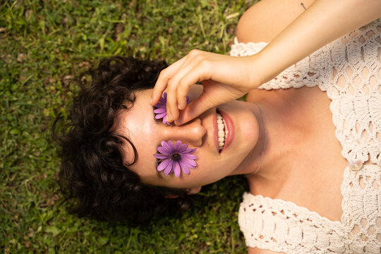 Portrait of young woman laying on grass with flowers