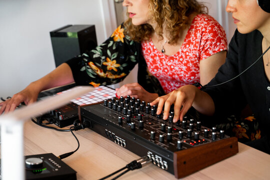 Friends playing midi controller at home music studio
