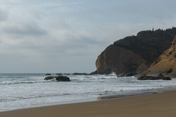 Long shot of the beach next to a mountain on a sunny day