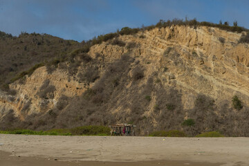 landscape of a trash polluted beach with a small stand next the mountains on a sunny day