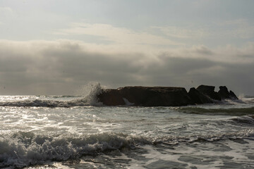 Wave crashing on a big rock on the beach during  a sunny day