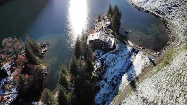 Aerial flyover above Seealpsee in Appenzell, Switzerland in winter with snow and pan up from the shores to the mountains - 4k