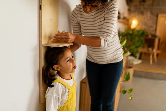 Mother measuring her daughter's growth