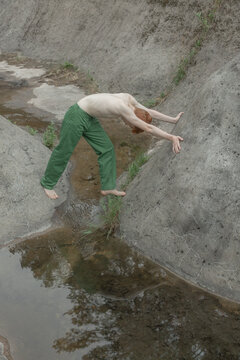 a man lies on the concrete with greenery by the pond