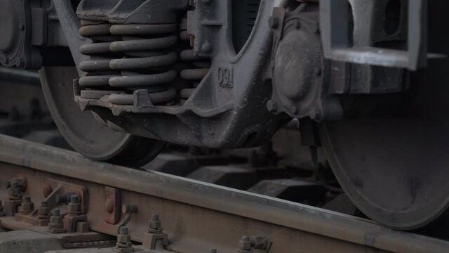 Cargo train rides on railroad moving slowly by rail at the station. Closeup of wheels on railway. Close up of wheeled pair of freight railway train. Transport concept. 