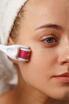 Woman applying derma roller on face